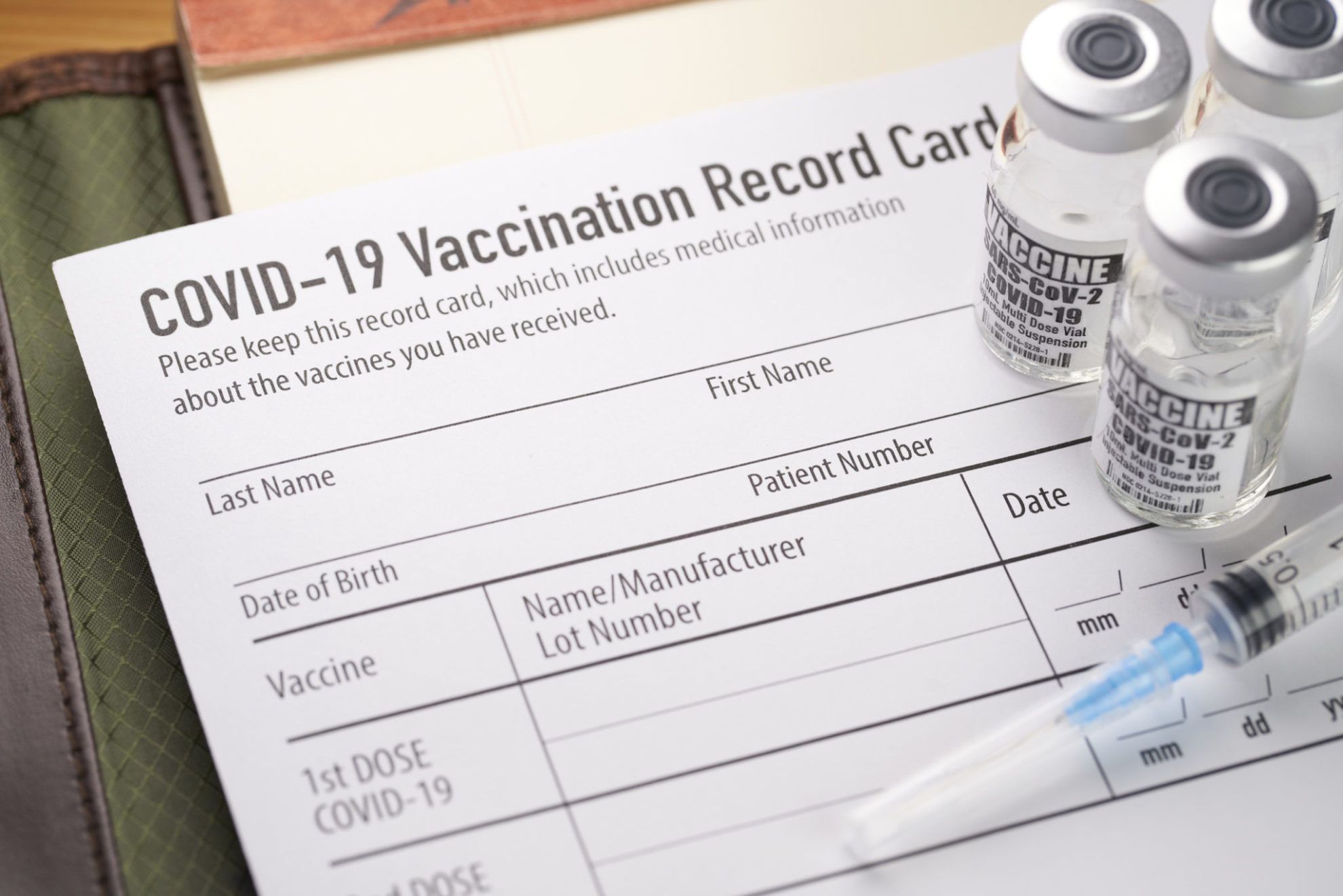 Covid-19 vaccination record card with vials and syringe. Covid-19 vaccination record card with vials and syringe.